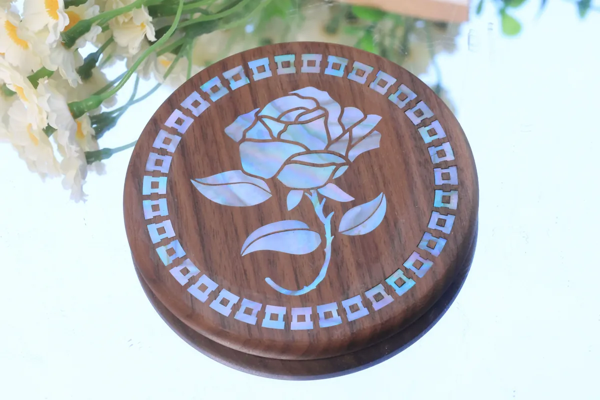 Rosa in madreperla intarsiata in un sottobicchiere di legno